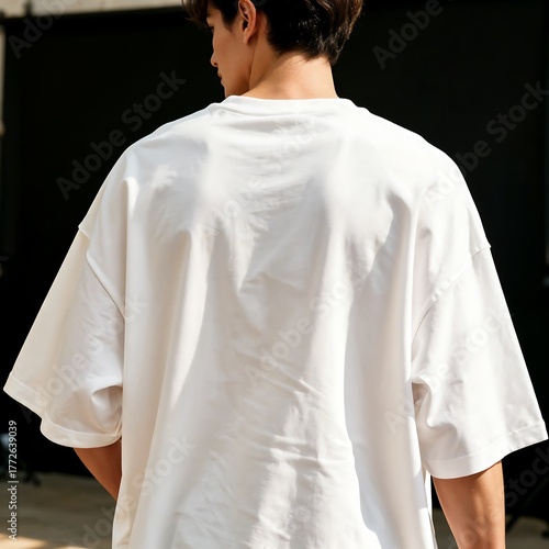 A man wearing a plain white oversized t-shirt from behind with his hands in his pockets