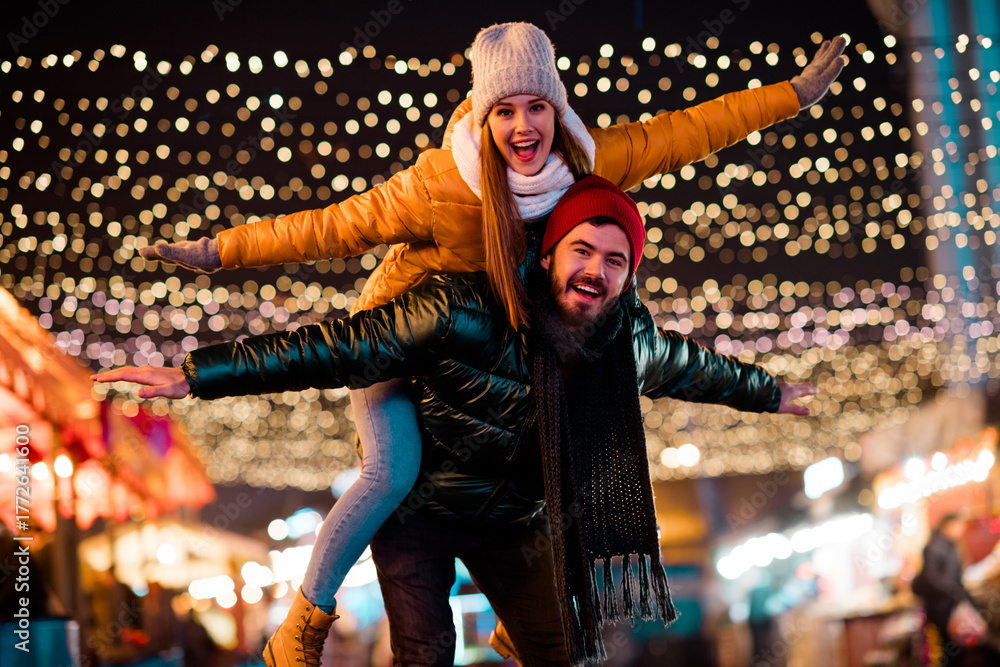 Fototapeta premium Delighted couple and friend enjoy festive street lights at a winter market full of joy and holiday glow