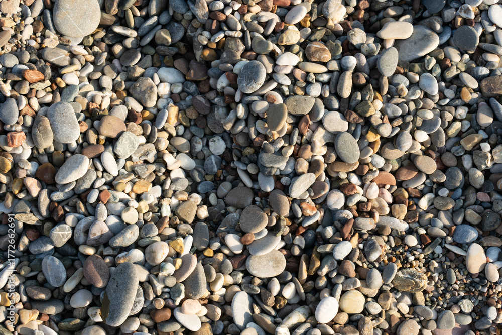 Naklejka premium Close-Up Of Smooth Multicolored Pebbles On A Pebble Beach Surface With Natural Texture