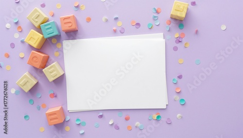 Blank greeting card, baby blocks and confetti on lilac backdrop, suitable for children's celebration