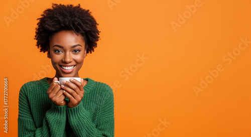 Young black woman wearing green sweater cheerful expression holding coffee cup isolated on orange background