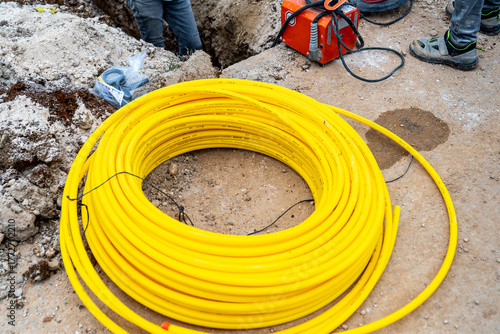 A roll of yellow polyethylene (PE) pipe. This type of pipe is typically used in natural gas pipelines. The photo shows the preparation phase for an underground natural gas pipeline installation.