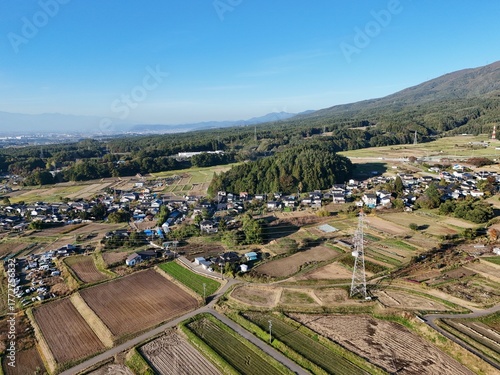 Wallpaper Mural A rural area with a few houses and a large mountain in the background. The sky is clear and the sun is shining Torontodigital.ca