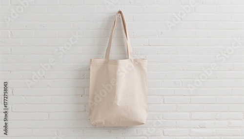 Blank reusable fabric tote suspended on a white brick backdrop, plastic-free and waste-free