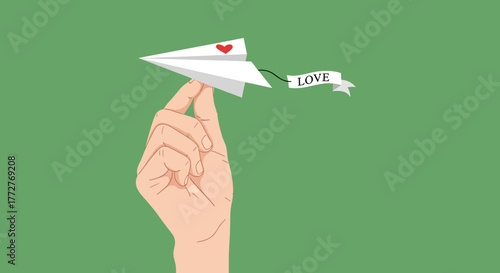 A paper airplane with a heart and a love banner held gently by a hand against verdant background