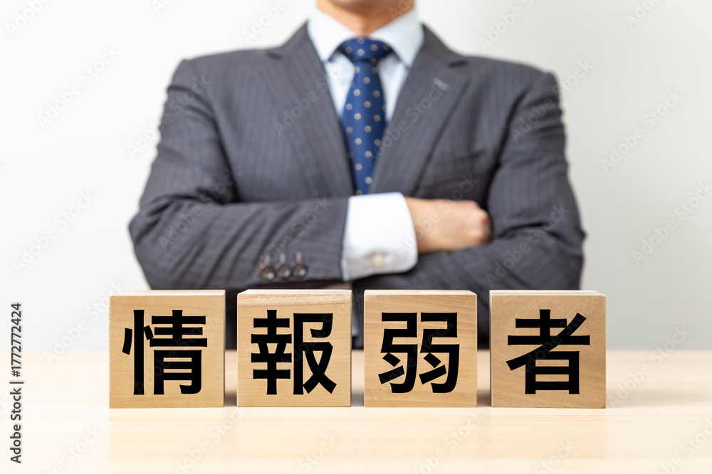 Obraz premium 「情報弱者」と書かれたブロックと腕組みをするビジネスマン