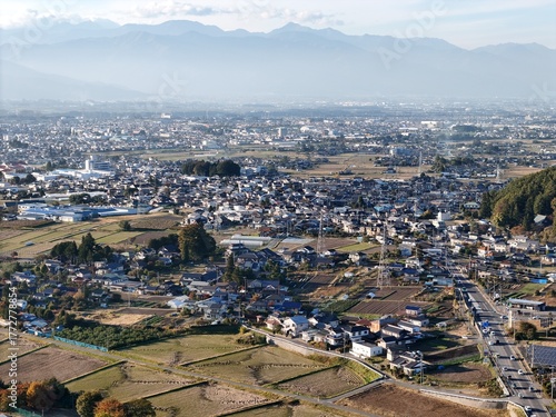 A city with a lot of houses and a few cars. The sky is cloudy and the sun is not very bright