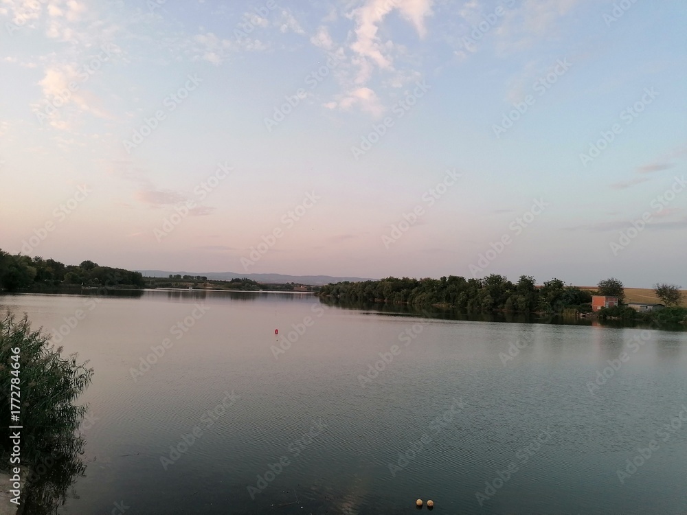 Naklejka premium Still Lake Water at Sunset or Twilight with Pastel Sky Colors and Horizon