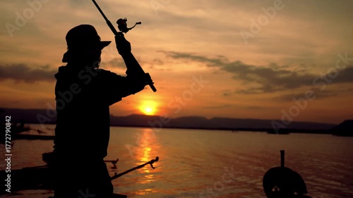 A fisherman enjoys peaceful sunset fishing on a quiet lake, casting his line into the calm water.