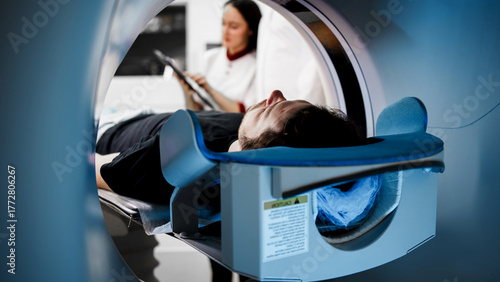 Patient undergoing CT scan in modern medical facility, with technician monitoring process, showcasing advanced imaging technology and healthcare environment