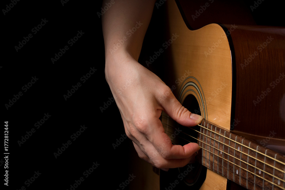 Fototapeta premium woman hand plays the guitar on black background, learning music. lifestyle