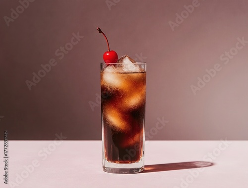 Tall glass of dark cola with ice and a cherry garnish