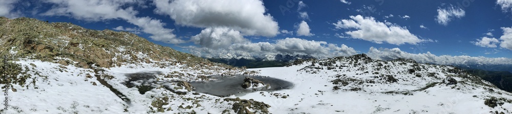 Fototapeta premium Snowy mountain landscape panorama with small frozen lake and clear blue sky
