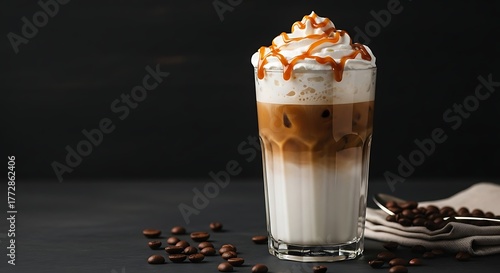 Iced caramel latte coffee in a tall glass with whipped cream and dark background