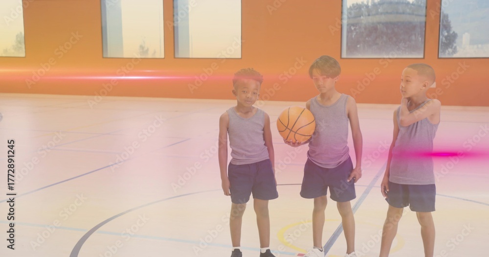 Naklejka premium Standing three boys wearing matching grey sportswear at gym court, with basketball and court lines