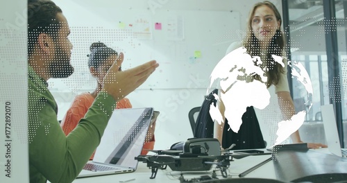 Team of four collaborating on strategy at conference table with drone and world map overlay