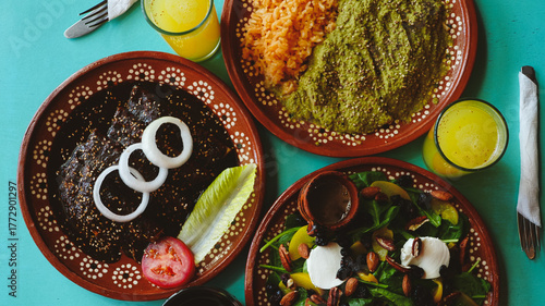 Mesa servida con enchiladas, ensalada fresca y pollo en salsa verde; bebidas tradicionales acompañan el conjunto.