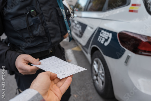 Police officer delivering document to driver during traffic control