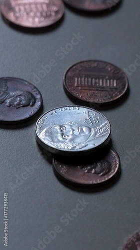 Nickels and pennies thrown on a table (vertical video). American money.