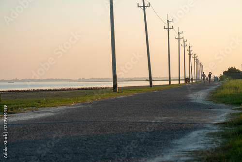 A tranquil road lined with power poles during twilight, stretching into the horizon