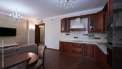 Wallpaper Mural Cozy living space featuring a sofa, round table, and dining chairs. Modern kitchen with wooden cabinets and white countertops. Wall-mounted TV and elegant chandeliers complete the room. Torontodigital.ca