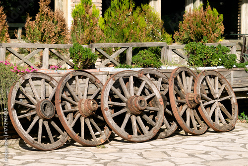 A group of old wooden wheels used as yard decoration.