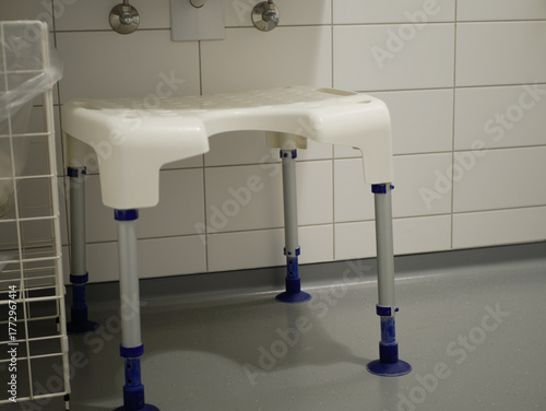 Adjustable white shower chair with non-slip feet in hospital bathroom, accessibility equipment for elderly and disabled patients ensuring safety and hygiene in healthcare, pro photo. High quality