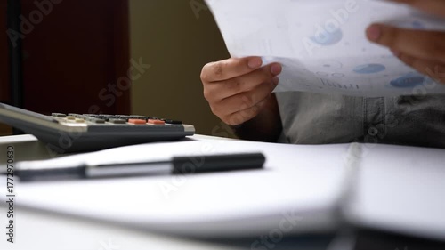 Person using a calculator with a notepad and pen on a desk shot