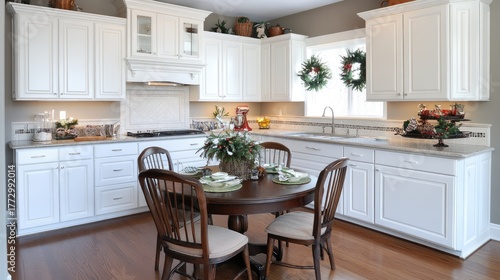 A welcoming kitchen features white cabinets, a central dining table, and Christmas decorations creating a festive holiday atmosphere