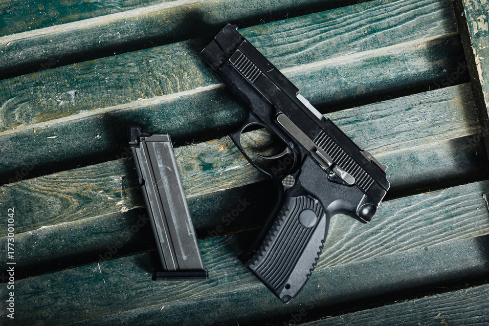 Obraz premium military firearm setup, service pistol on ammunition box, olive drab pistol resting against wooden