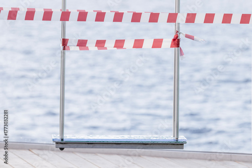 A wet swing after the rain, fenced off with white and red warning tape.
