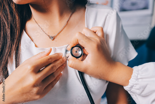 Doctor examining patient with stethoscope in hospital bed. Medical care and healthcare concept in a clinical setting.