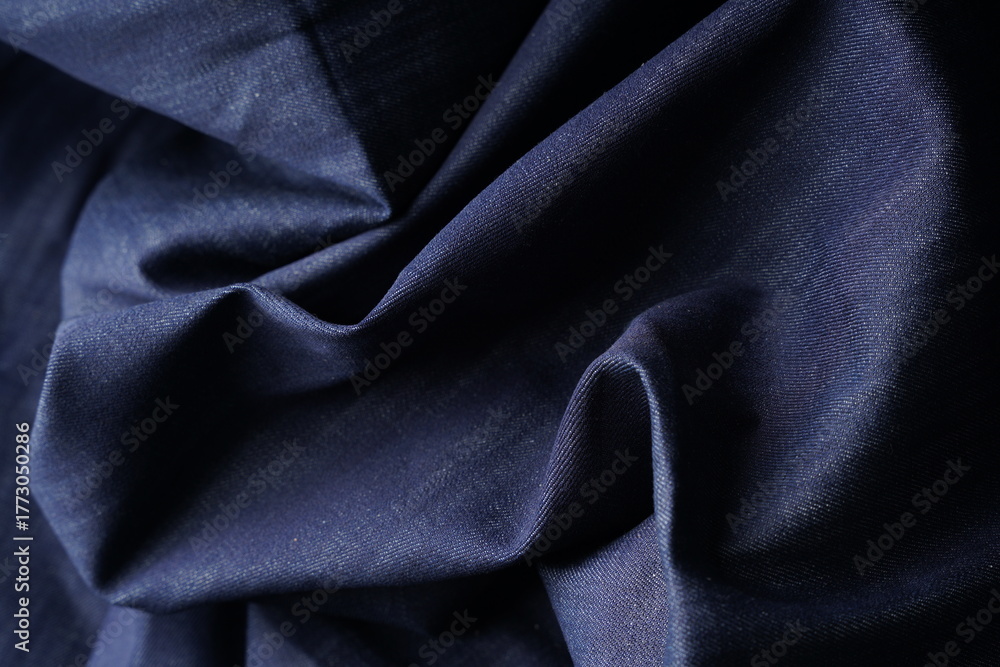 Obraz premium Wrinkled Denim Cloth Close-Up Texture Background. Detailed Denim Textile Background in Dark Blue Color. High Quality Denim Fabric Texture for Fashion and Textile Use. Indigo Denim Textile Background