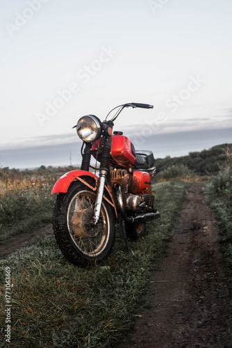classic motorcycle showcased on muddy trail with glowing headlamp and textured chrome surface