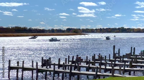 Fishing boats motor by wooden docks on the Rainy River, which borders the United States and Canada, near Baudette, Minnesota on a sunny autumn morning.