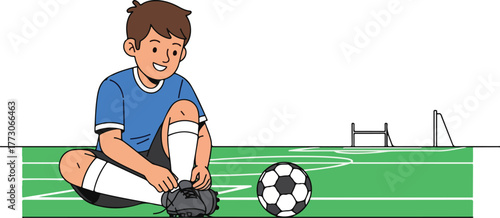 A young boy in a blue shirt sits on a soccer field tying his cleats, with a soccer ball nearby and a goal in the background.