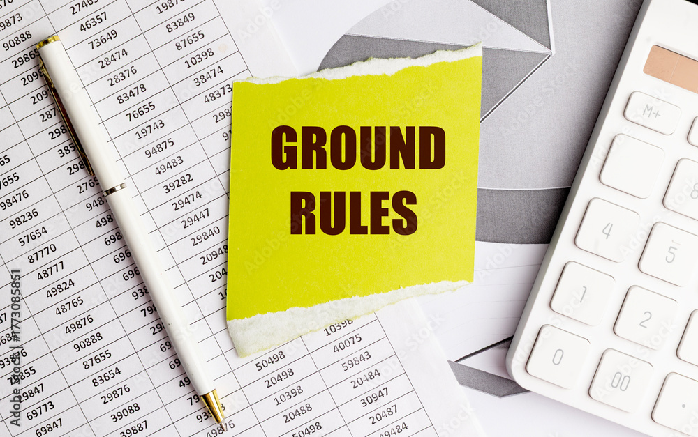 Fototapeta premium Yellow torn paper with text ground rules on office documents with pen and calculator