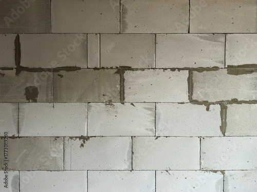 Unfinished gray concrete block wall with fresh mortar joints and subtle water stains, evoking raw industrial construction texture