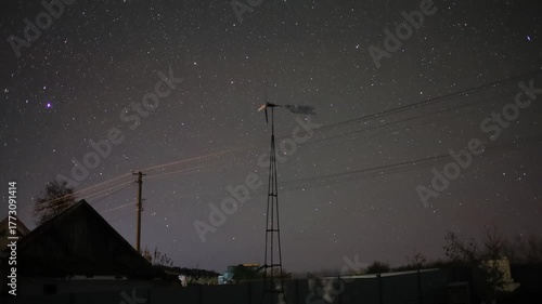 Starry night sky moving over rural wind turbine