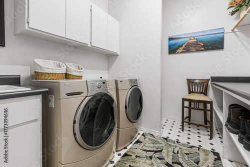 An interior laundry room that includes a washer, dryer, and a chair