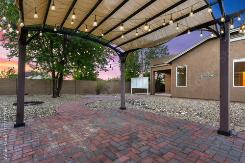 A brick patio with a canopy and lights in front of a house