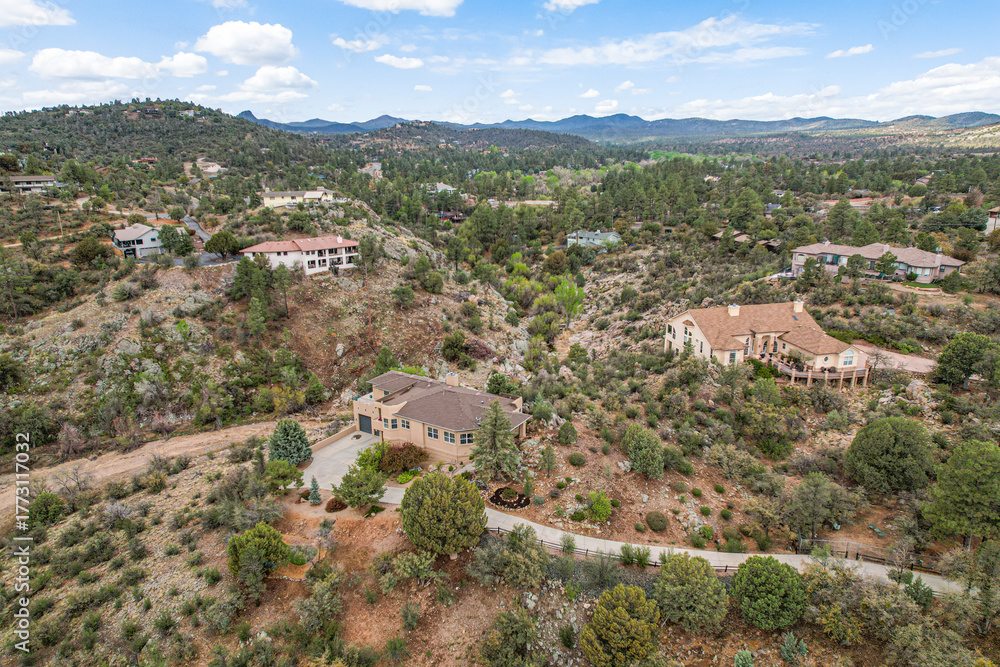 Fototapeta premium Aerial view shows a house on a hill, amid lush trees and greenery