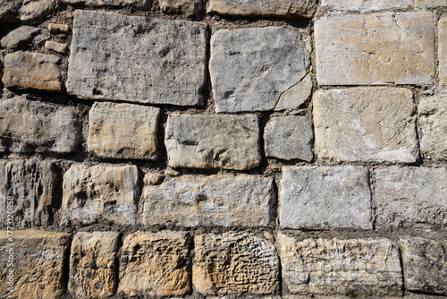 background, stone wall structure, constructed from light-colored stones of varying sizes, with some stones featuring darker veins or inclusions