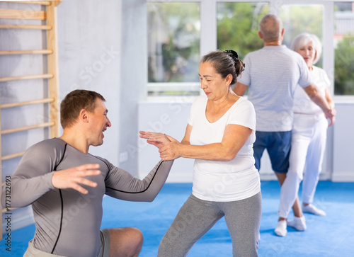Fotografie Senior woman train in pair with middle-aged coach to strike and reflect blows of enemy
