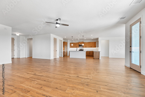 A spacious, vacant room with hardwood flooring and a ceiling fan