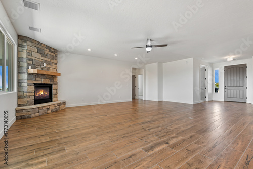 A spacious, vacant room with hardwood flooring and a ceiling fan