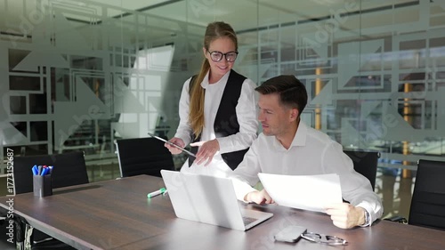 Two professionals review documents together.