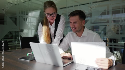 Two professionals talk at a meeting table.