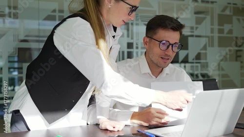 Colleagues work together on a laptop in an office