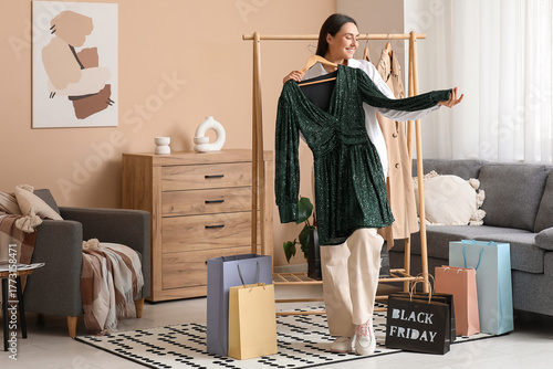 Foto Young woman trying on dress among shopping bags at home